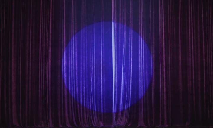 closed purple curtain with blue spotlight in the center
