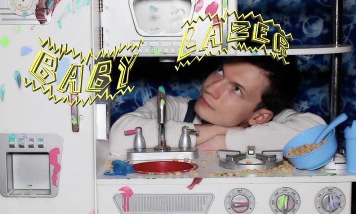 Baby Lazer poster with man looking through a white toy stove