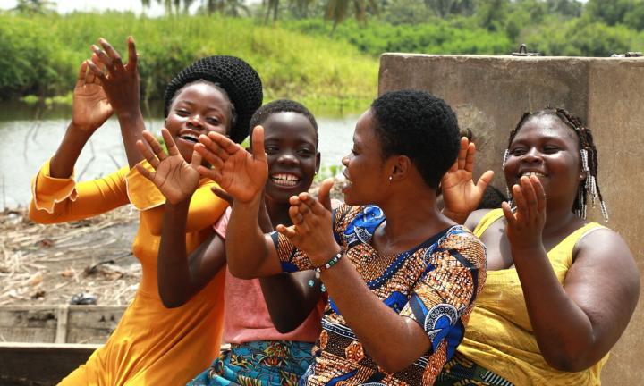 four girls in colorful clothes clapping hands and laughing