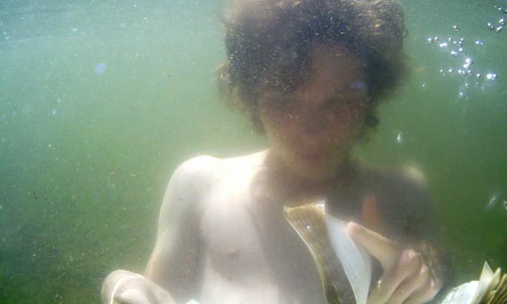 Young person turning pages of a book under water