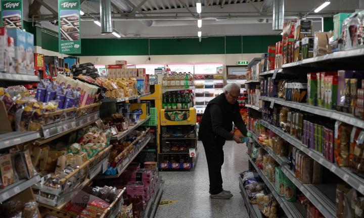 man leaning over to get something from a lower shelf in the aisle of a grocery store