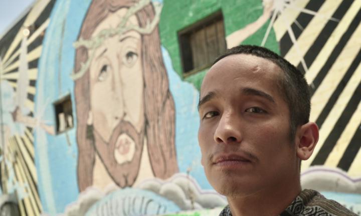 young man in front of a mural of Jesus with a crown of thorns