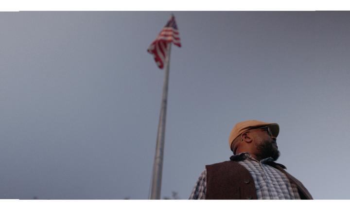 poet Sean Hill in front of a tall pole flying an American flag
