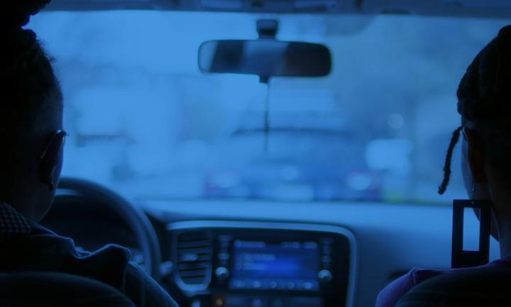 blue toned picture from the back of a car of two people in the front seat