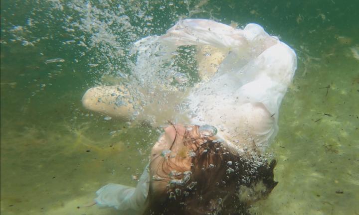 underwater photo of figure in white dress twirling 