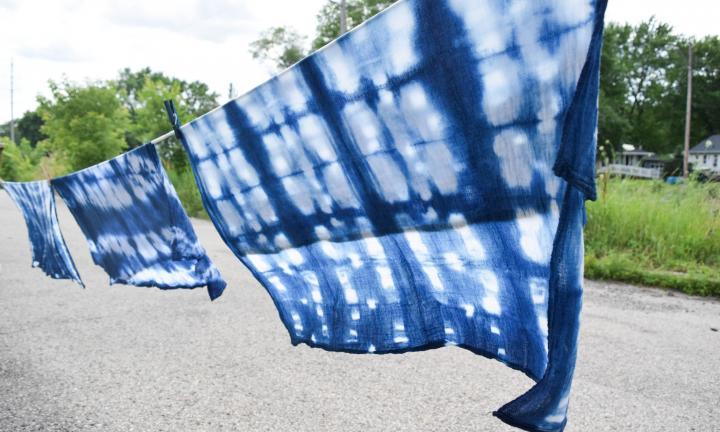 shibori sheets drying on a line with pavement and trees behind