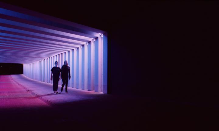 Photo of two silhouette figures walking down a hallway.