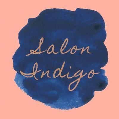 words "Salon Indigo" written in cursive in blue paint against a peach background