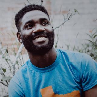 Portrait of author in blue and orange shirt, smiling