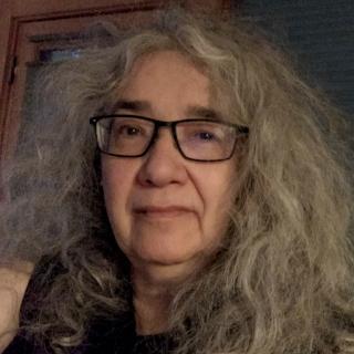 Writer with wavy gray hair and black framed glasses