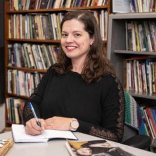 Portrait of author signing book with bookshelves in the background