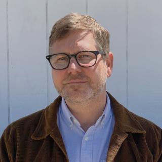 Author wearing brown corduroy and black glasses.